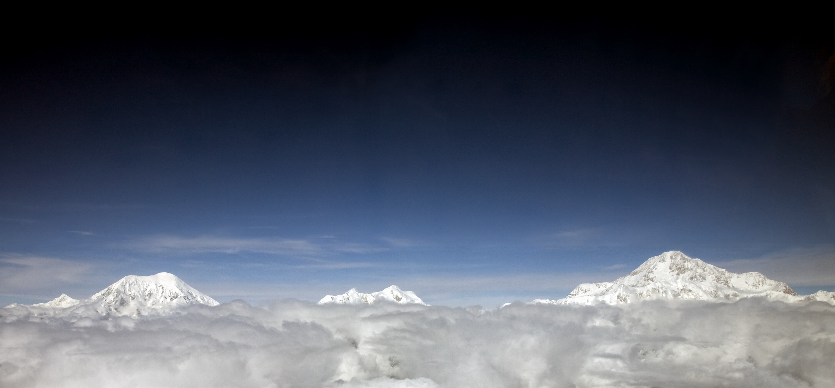 Mount Foraker, Mount Hunter, and Denali rising above a sea of cloud